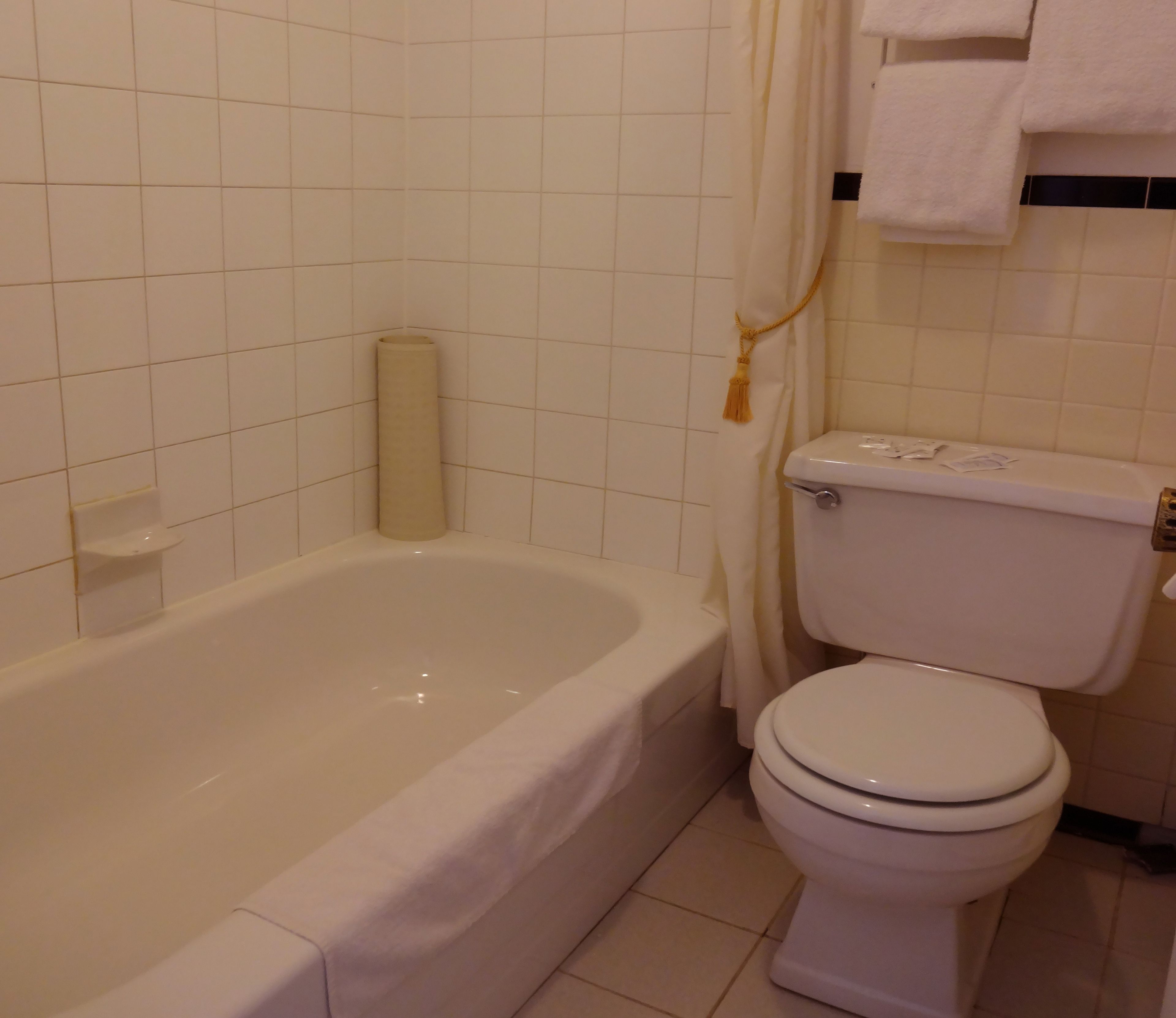 A bathroom with a bathtub, toilet, and a towel rack.