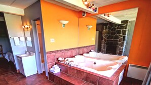 A modern bathroom with a large bathtub, a sink, and a mirror. - Motel Tremblant (Mont-Blanc)