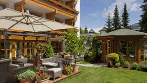 Un espace extérieur aménagé avec des meubles en osier, un coin salon abrité et une petite structure en bois.