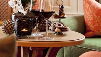 Una sala de estar acogedora con chimenea, un pequeño árbol de Navidad, y una mesa con bebidas y aperitivos.