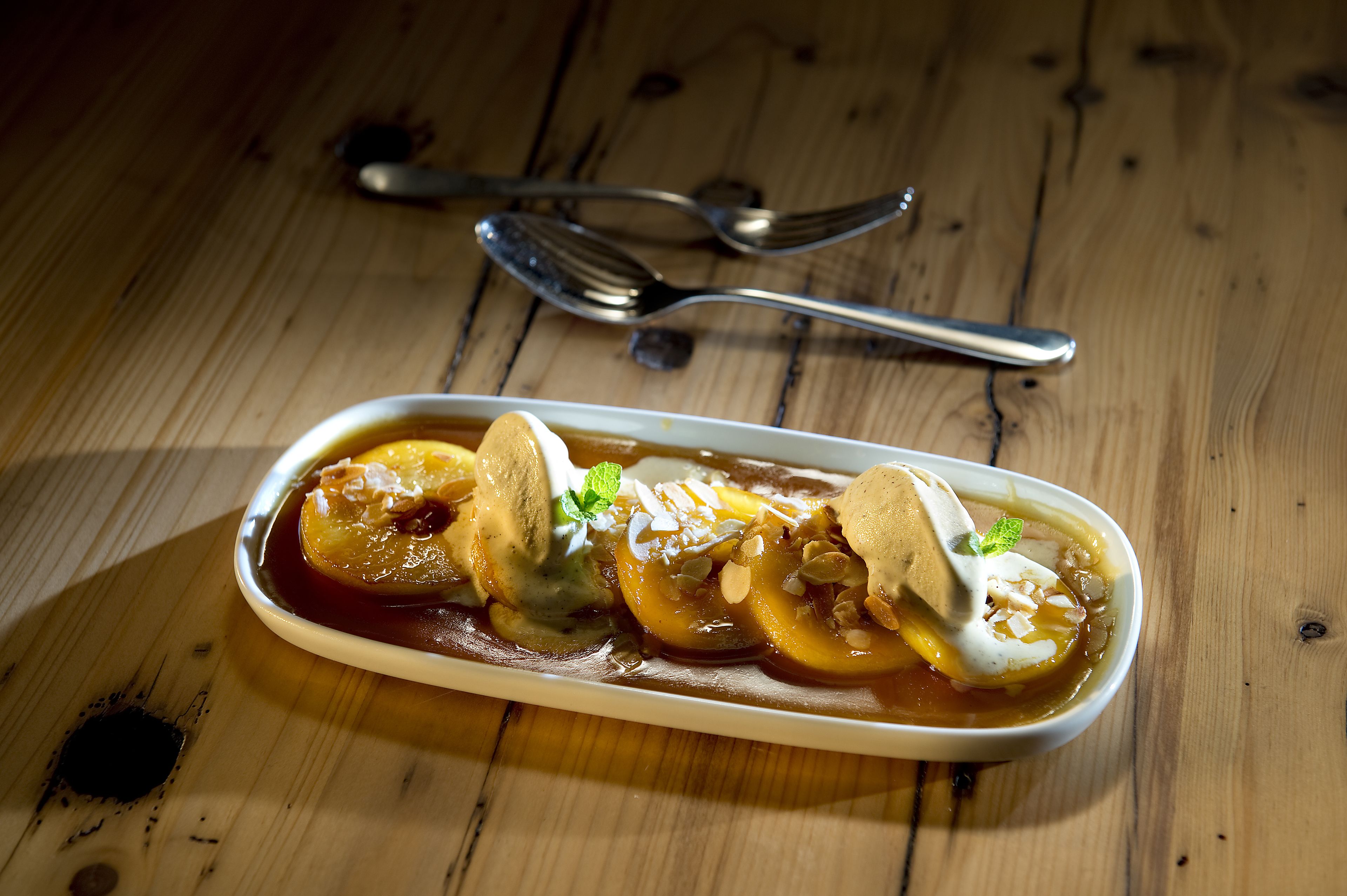 A dessert dish on a wooden table with a spoon and fork nearby.
