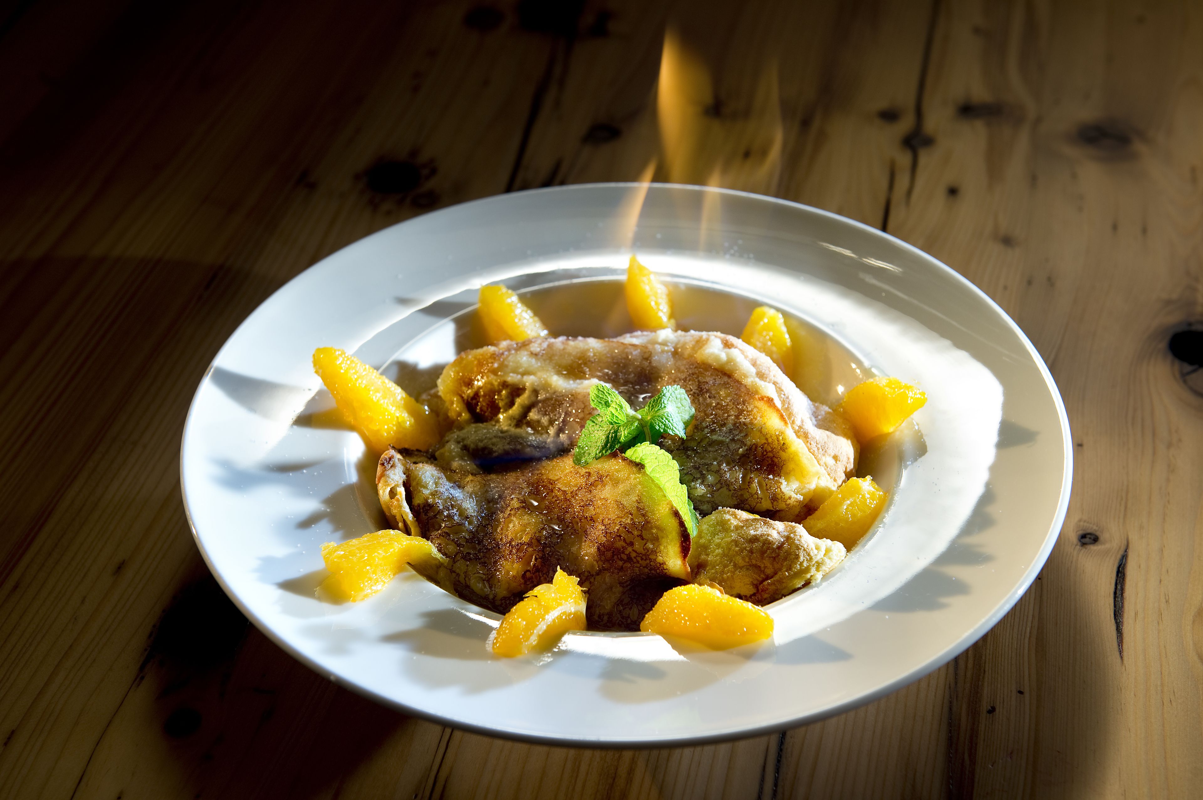 Un plato de comida con carne y rodajas de naranja sobre una mesa de madera.