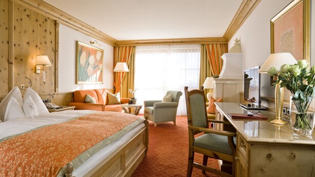 A hotel room with a large bed, a desk with a computer, a chair, and a sofa.