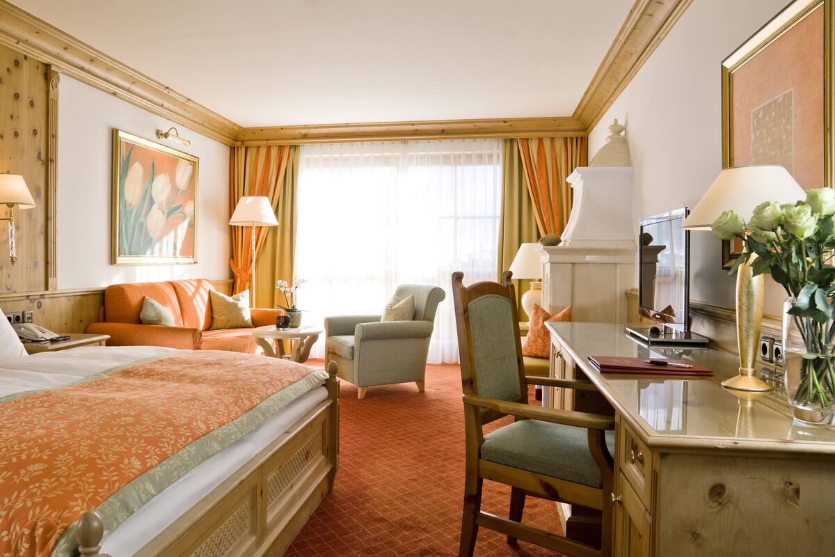 A hotel room with a large bed, a desk with a computer, a chair, and a sofa.