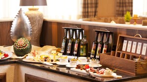 Une table de buffet proposant divers aliments, notamment des fromages, des viandes et des olives, ainsi que des bouteilles d’huile d’olive.