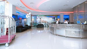 A modern lobby with a reception desk, seating area, and a glass elevator. - Palm Seremban Hotel (Seremban)