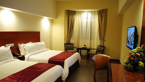 A hotel room with two beds, a desk, a chair, a TV, and a window with curtains. - Palm Seremban Hotel (Seremban)