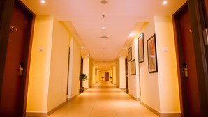 A hotel corridor with doors on both sides, recessed lighting, and framed artwork on the walls. - Palm Seremban Hotel (Seremban)