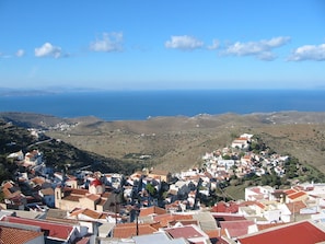 Une ville côtière avec des maisons à étages, une église imposante surmontée d’un dôme rouge et une vue sur la mer.