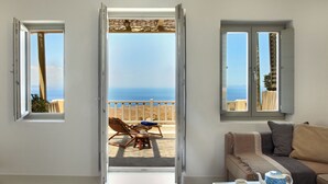 Una habitación con balcón, sofá, mesa de centro y vista al mar.