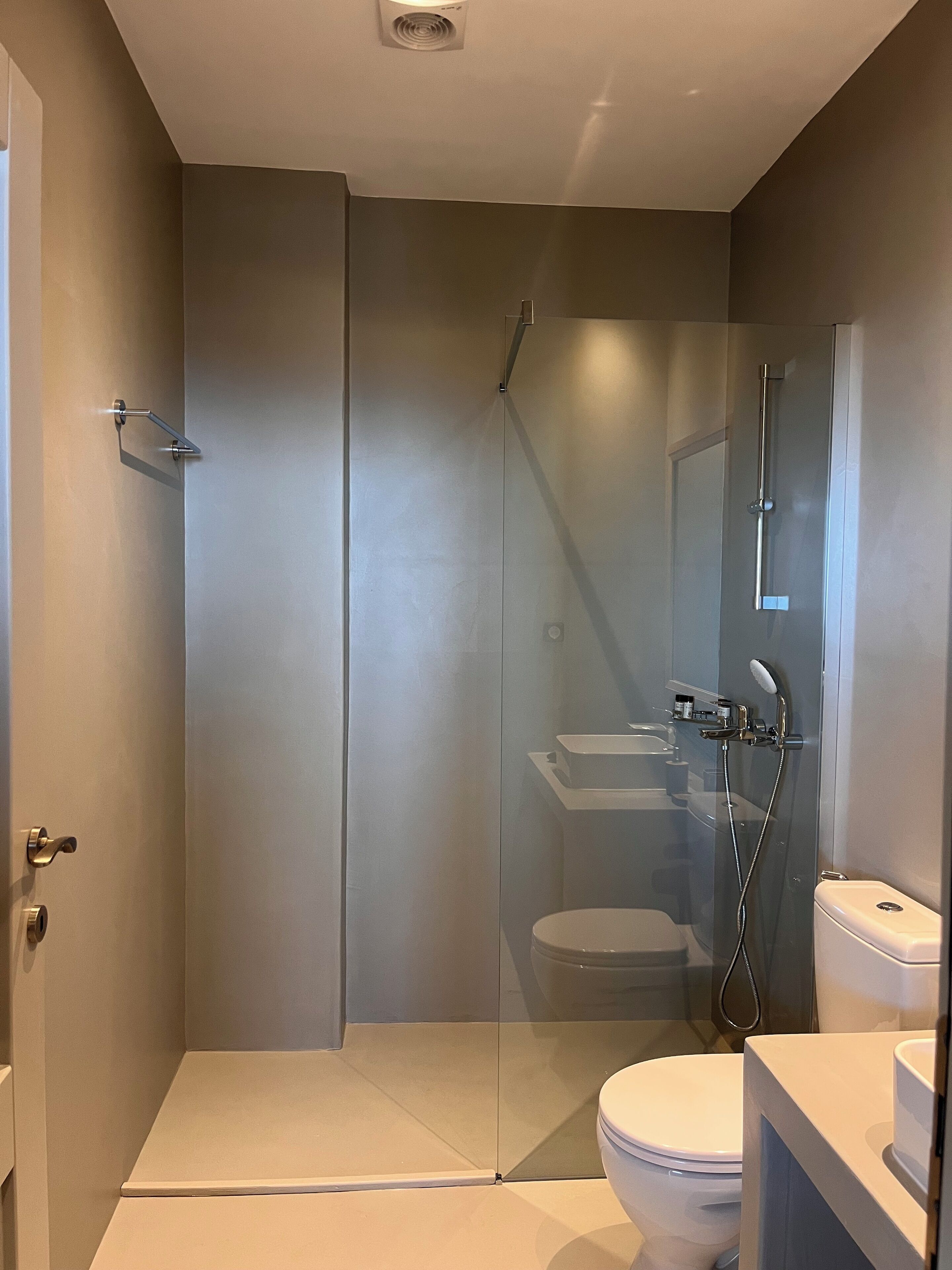 Un baño moderno con ducha de vidrio, inodoro y lavamanos.