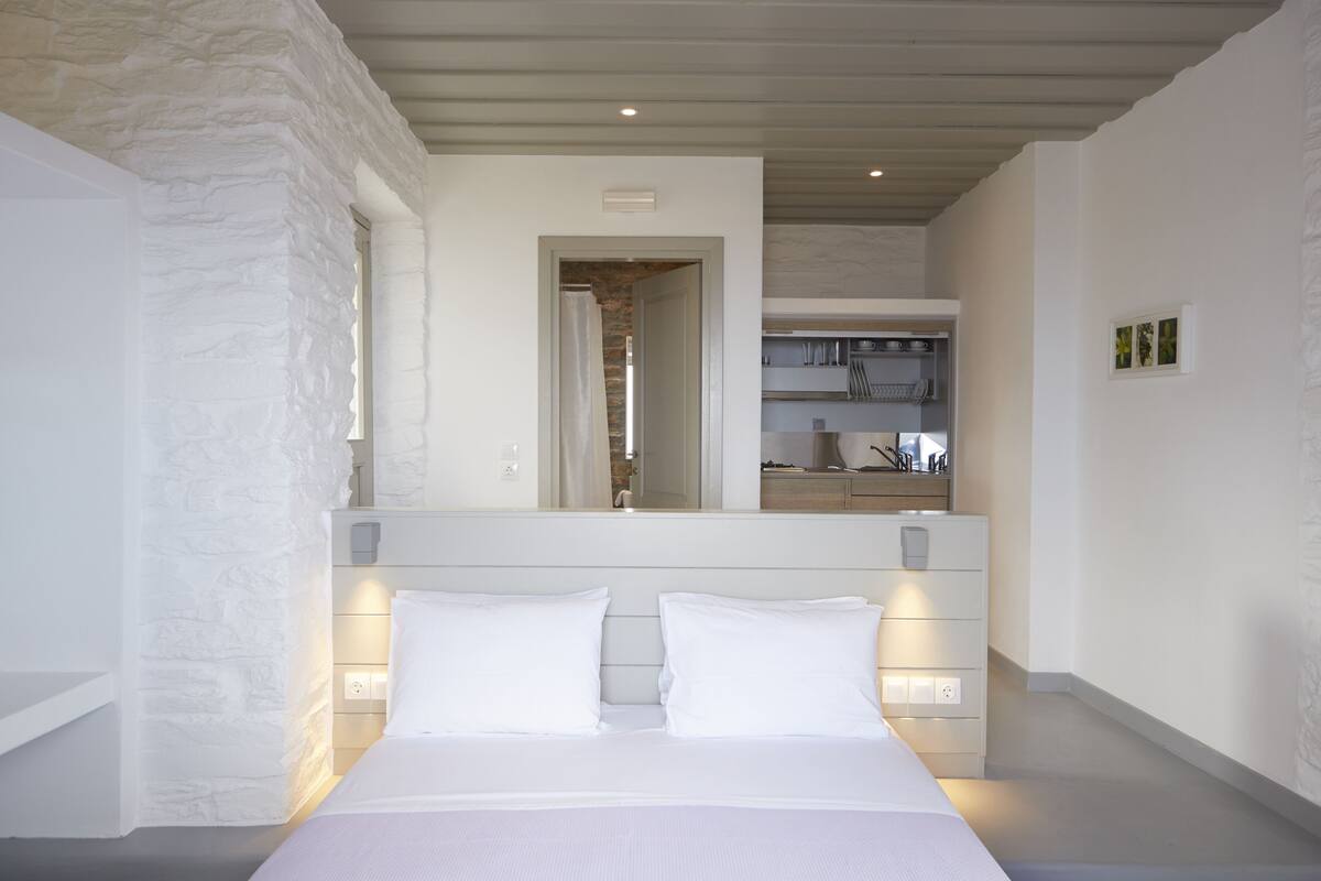 Ein Schlafzimmer mit einem großen Bett, weißen Wänden und einer Wand aus Naturstein.