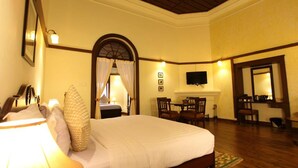 A hotel room with a large bed, a desk, a fireplace, and a television. - Hotel Chennai Le Palace (Chennai)