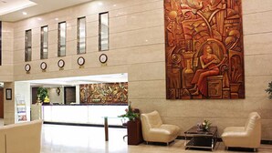 A lobby with a reception desk, seating area, and a large decorative wall. - Hotel Chennai Le Palace (Chennai)