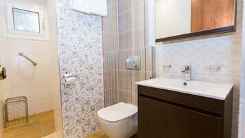 A bathroom with a toilet, sink, and shower area.