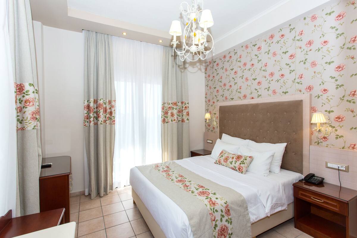 Una habitación de hotel con una cama grande, una mesita de noche, un escritorio y un candelabro.