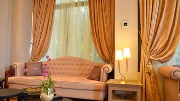 Una sala de estar bien iluminada con un sofá beige, una mesita con un jarrón de flores y una lámpara en una mesita auxiliar.
