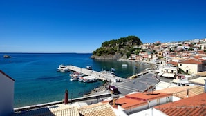 A coastal town with a marina, buildings with red-tiled roofs, and a hill with greenery. - Olympic Hotel (Parga)