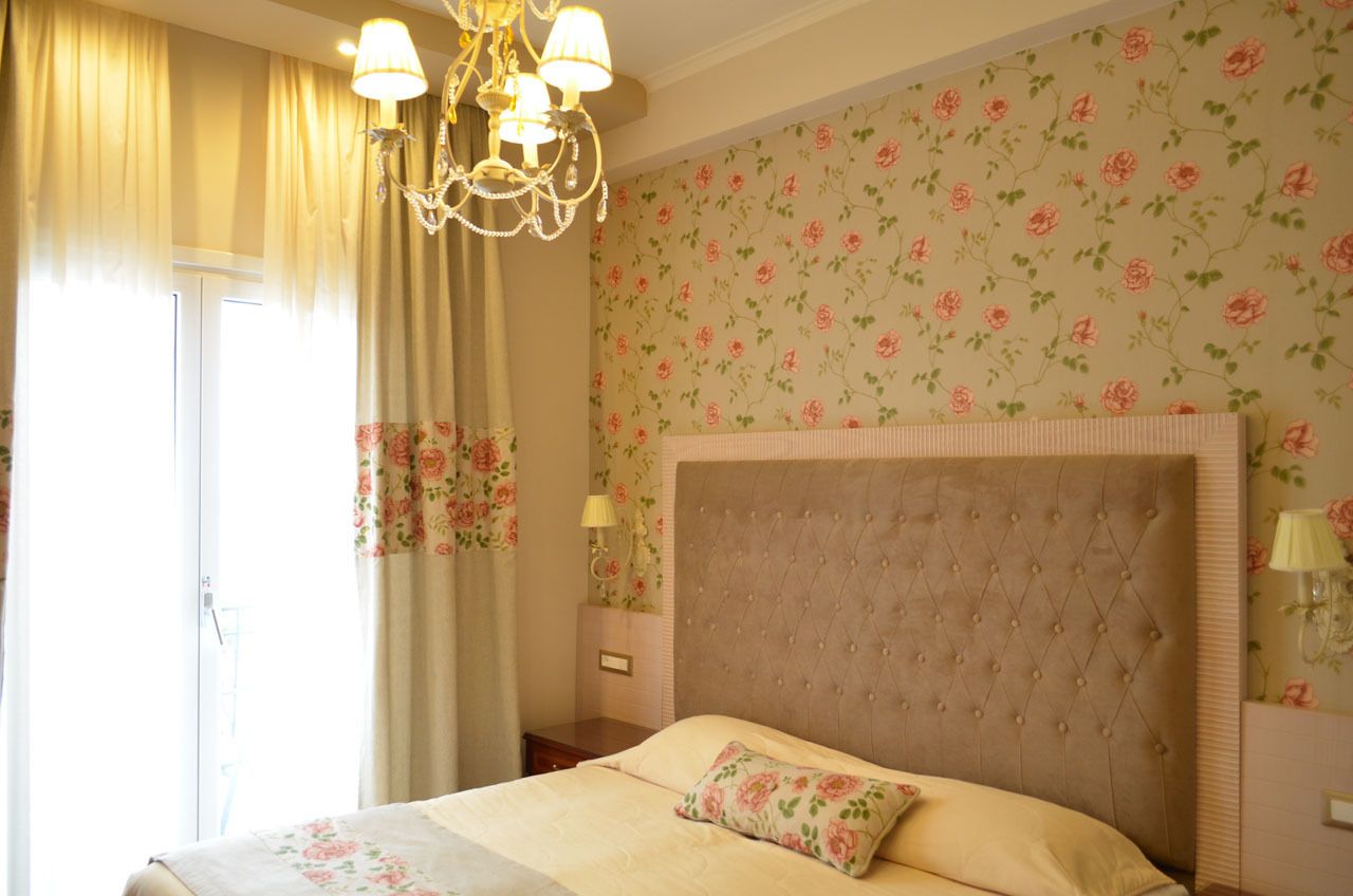 Un dormitorio con una cama grande, papel tapiz floral y un candelabro.
