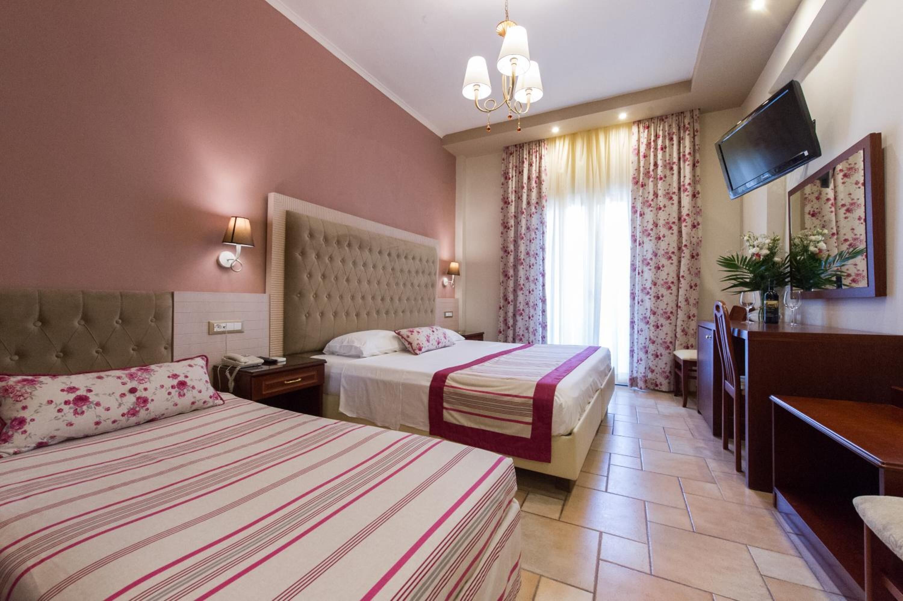 A hotel room with two beds, a television, a desk, and a chair.