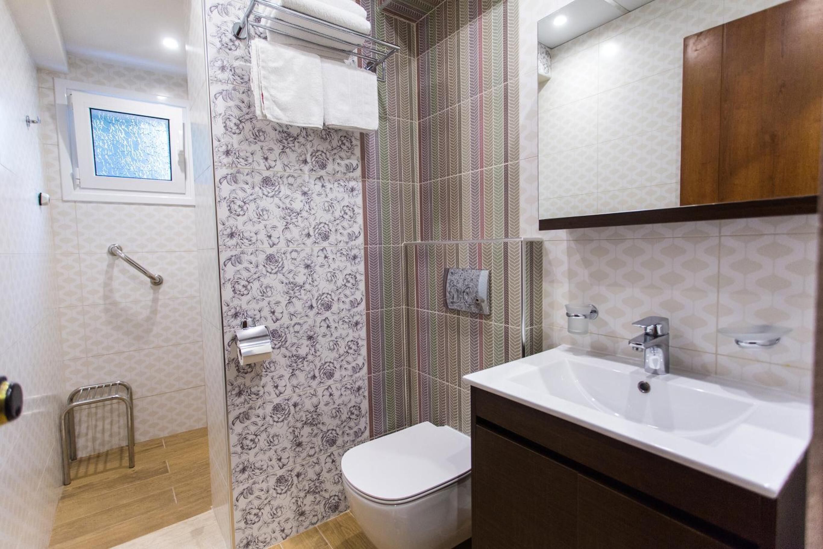 A bathroom with a shower, toilet, sink, and a window with a view.