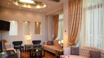 A modern living room with a sofa, armchairs, a coffee table, and a TV mounted on the wall.