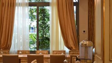 A dining area with a table set for four, a large metal lamp, and a view of greenery outside.