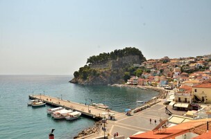 Un pueblo costero con muelle, barcos y edificios en una colina.