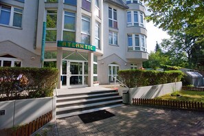 A building with a sign reading "ATLANTIC" at the entrance, featuring a modern design with large windows and a set of stairs leading up to the door. - Hotel Atlantic Berlin (Berlin)
