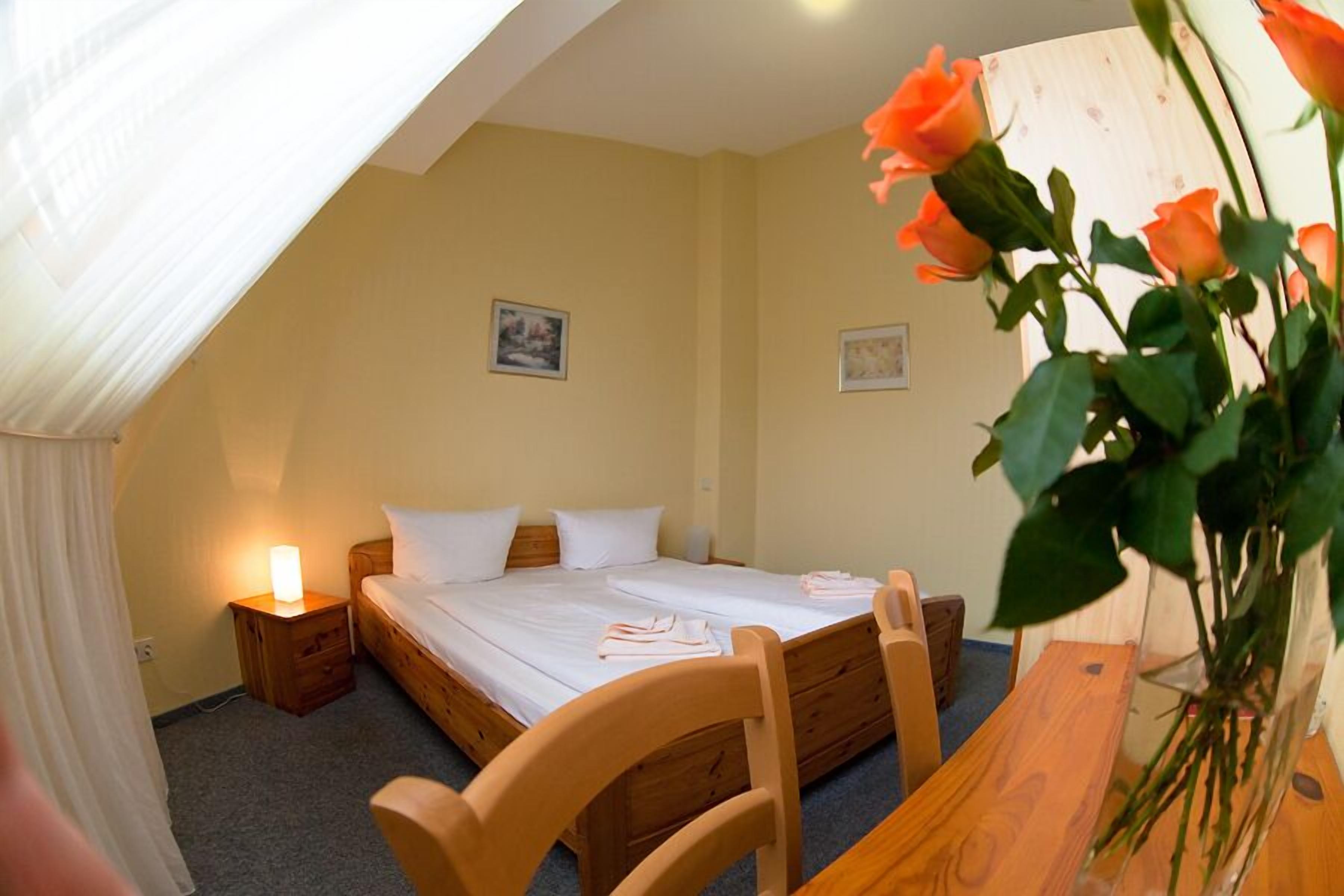 Ein Schlafzimmer mit einem Einzelbett, einem Nachttisch mit Lampe, einem Holzstuhl und einem Holzbüro.