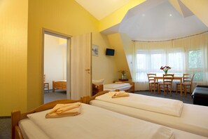 A hotel room with two beds, a dining area with a table and chairs, and a television on the wall. - Hotel Atlantic Berlin (Berlin)