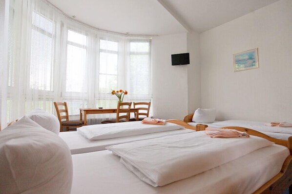 A hotel room with two beds, a TV, a painting, and a dining area with a table and chairs. - Hotel Atlantic Berlin (Berlin)