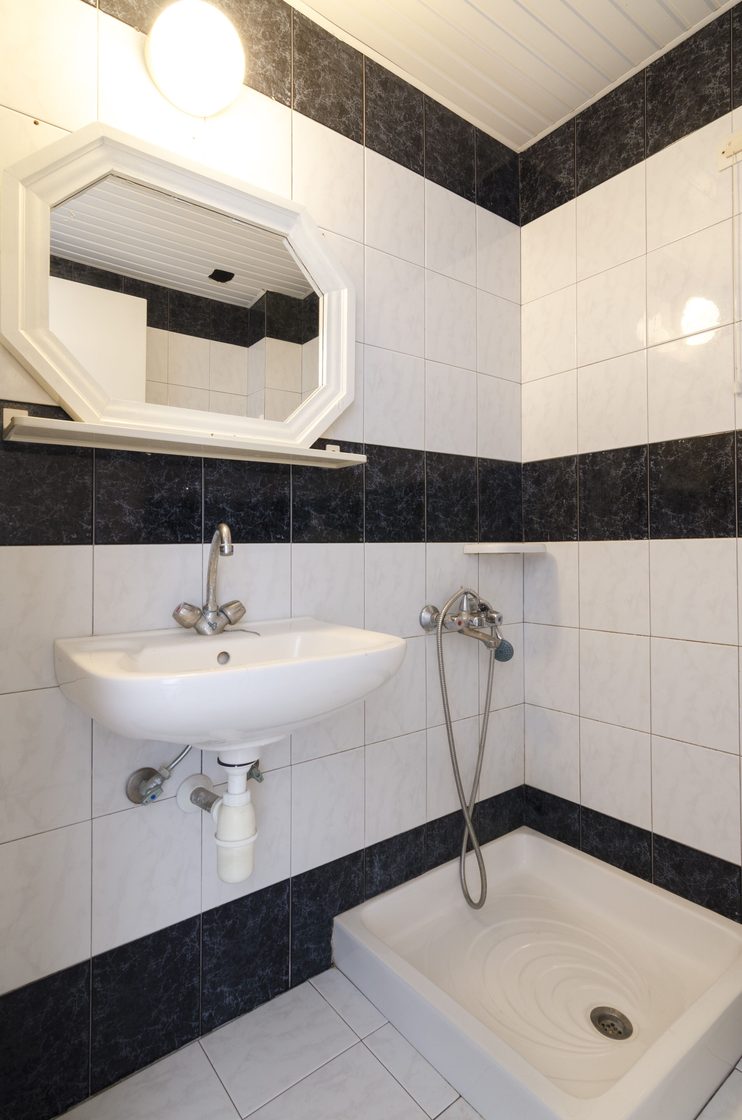 A bathroom with a white sink, a mirror, and a shower.