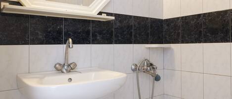 A bathroom with a white sink, a mirror, and a shower.