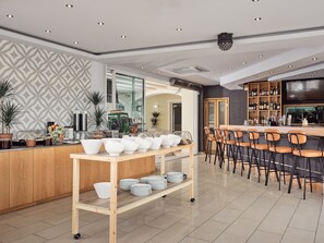 Una cocina moderna con barra de madera, espacio tipo bufé y zona de estar con taburetes.