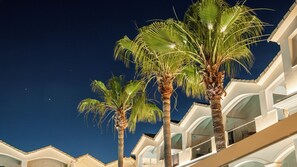 A hotel with multiple floors, palm trees, and a clear night sky. - Atlantis Hotel (Zakynthos)