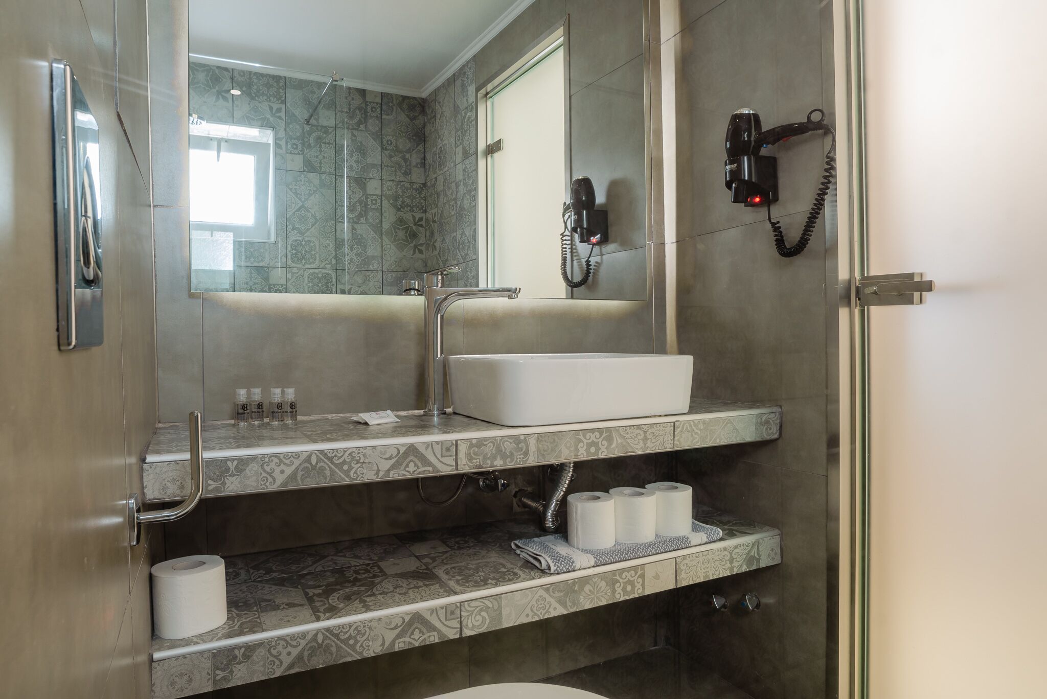 A modern bathroom with a large mirror, a sink, and a shower area.