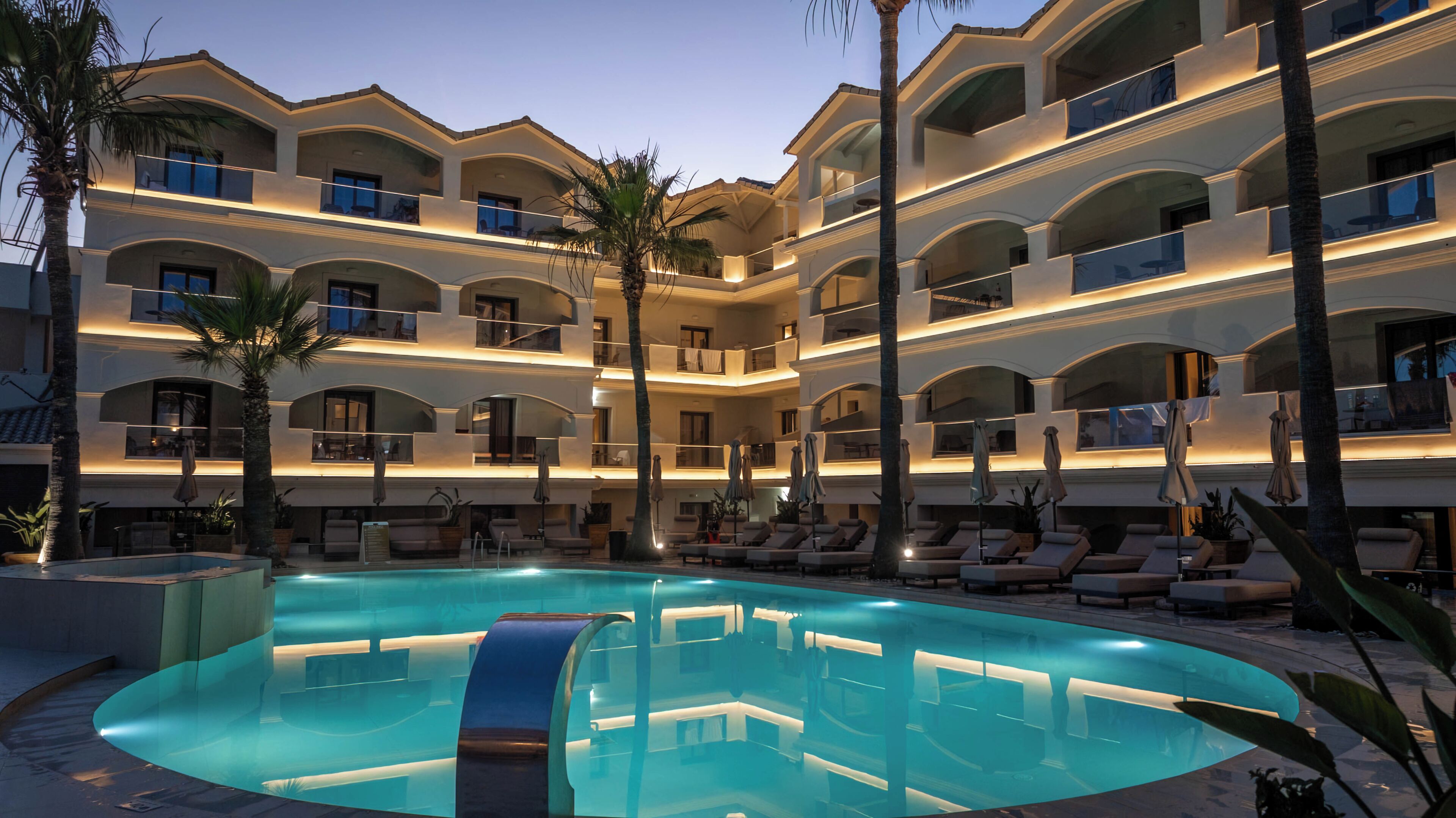 Un hotel de varios pisos con piscina, balcones y zonas de descanso.