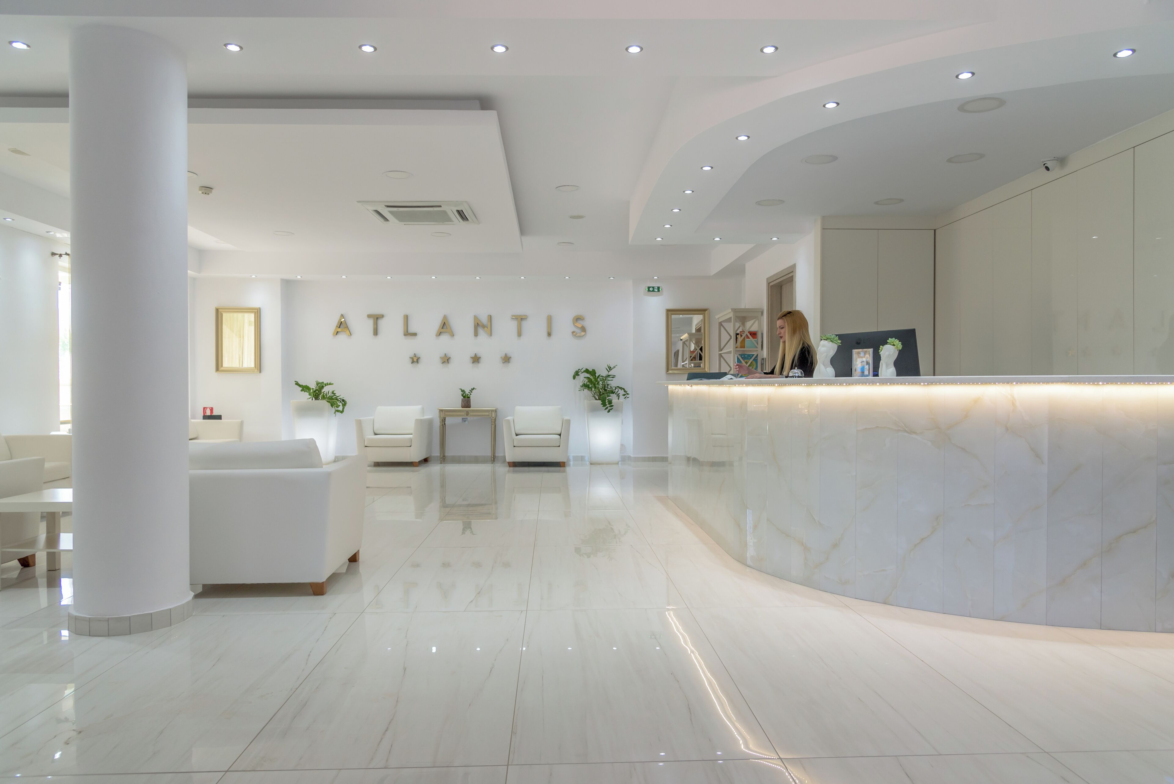 Una moderna zona de recepción con un mostrador de mármol, sofás blancos y un diseño limpio y minimalista.