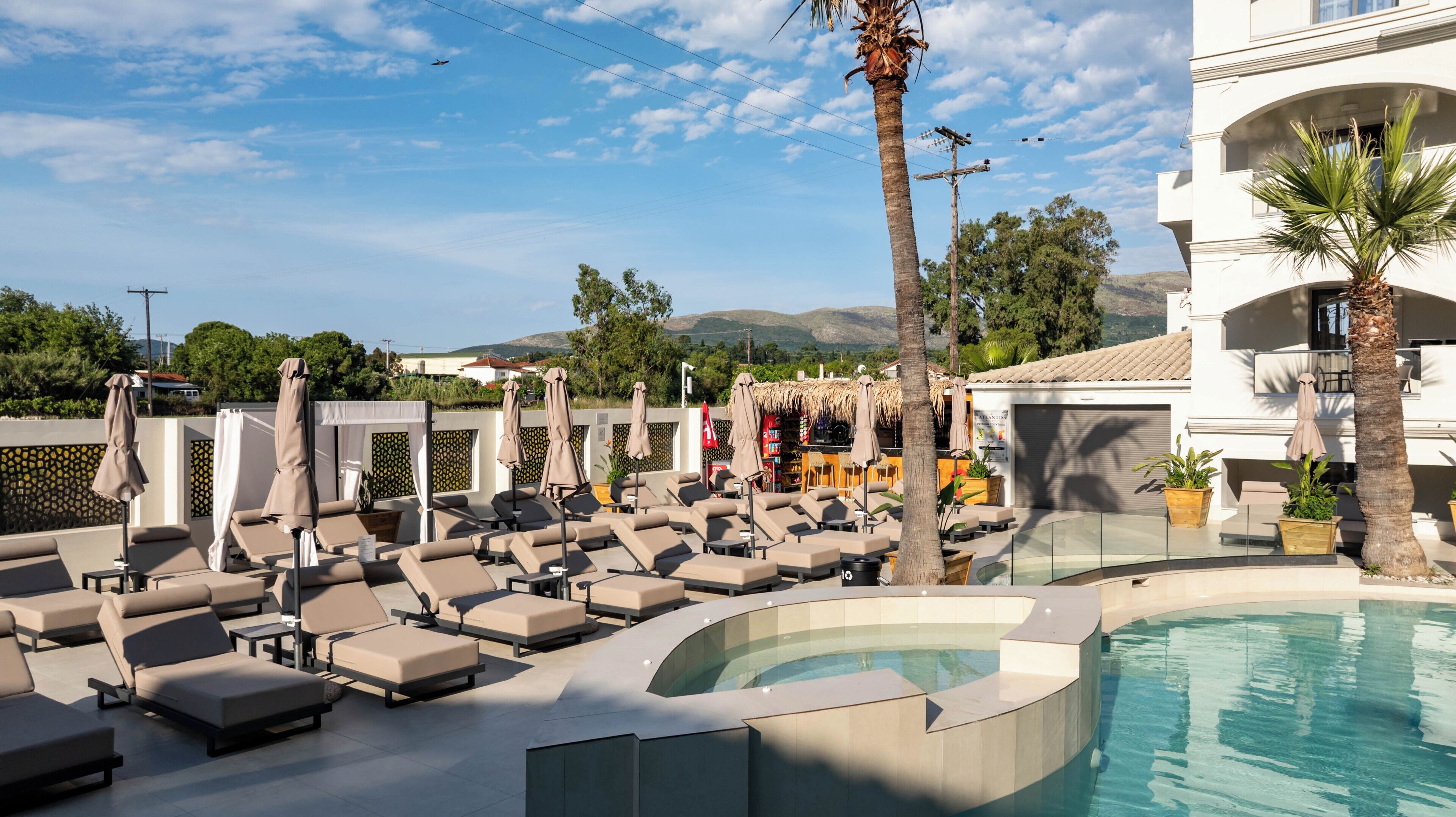 A poolside area with lounge chairs, a hot tub, and a bar area.