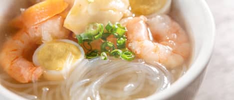 Un tazón de sopa de fideos con camarones, huevo y vegetales.