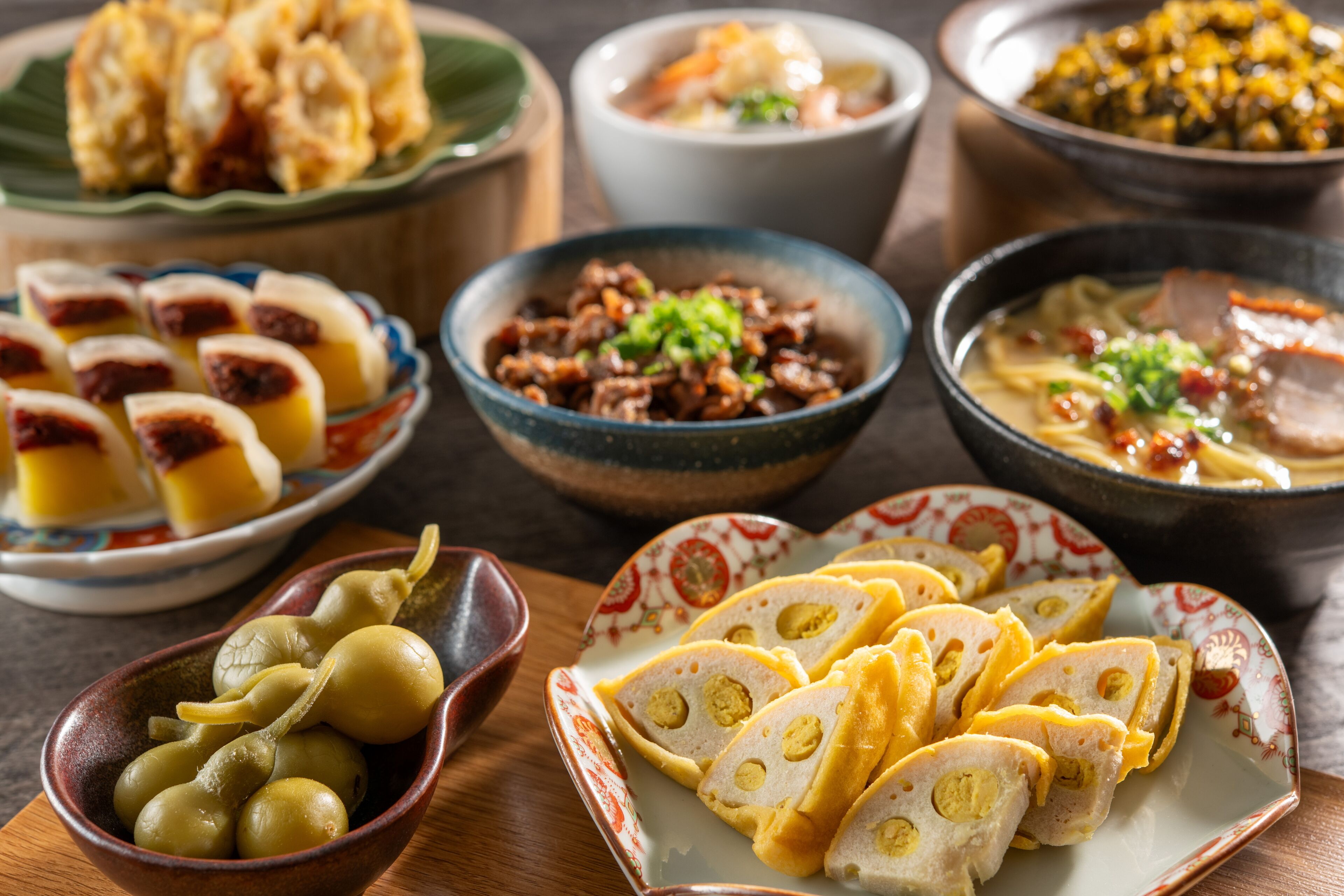 A variety of dishes including dumplings, a bowl of pickled vegetables, and a plate of sliced meat with vegetables.