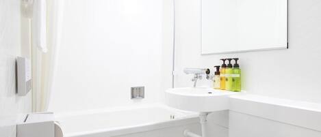 A modern bathroom with a bathtub, a sink, and a toilet. There are toiletries on the sink and a towel rack on the wall.