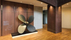 A modern interior with a large metallic sculpture, wooden panel walls, and a brick column. - HOTEL MYSTAYS Kumamoto Riverside (Kumamoto)