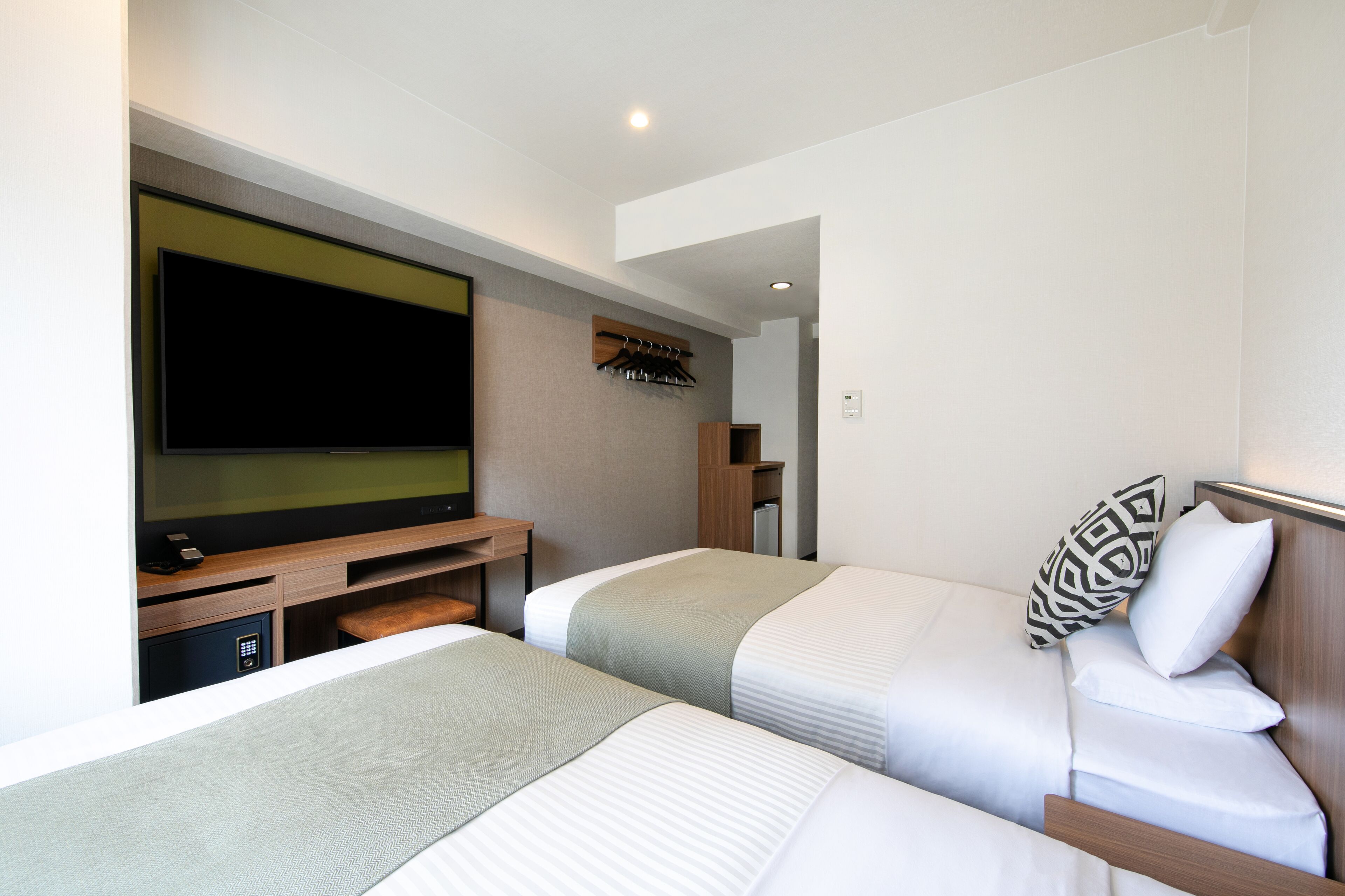 A hotel room with two beds, a TV, and a wooden cabinet.