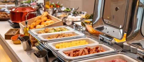 Un bufé con diversas opciones de comida, incluyendo carnes, quesos y pasteles.