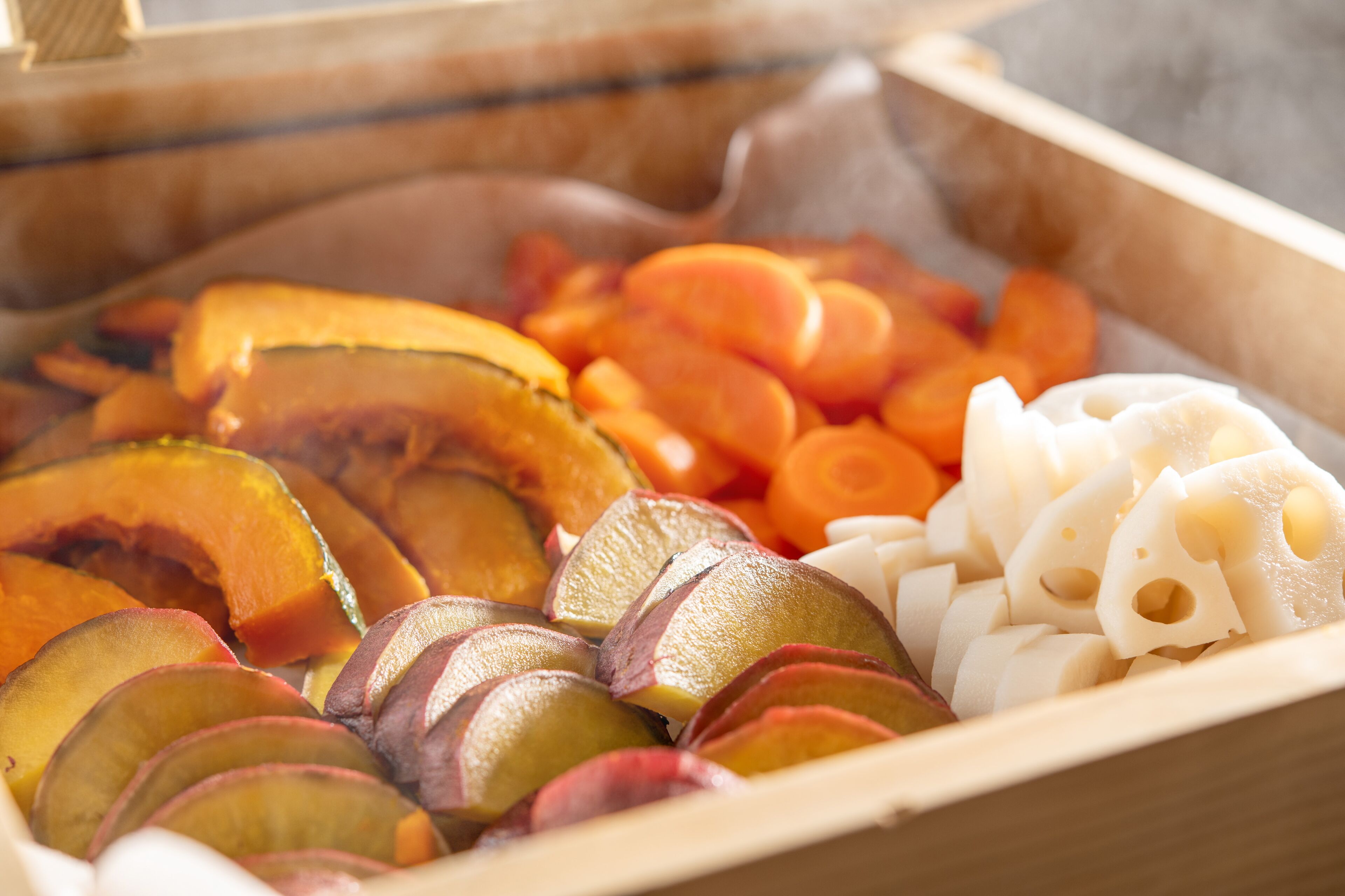 A wooden box containing sliced fruits and vegetables.