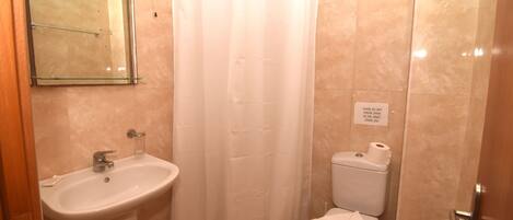 Un baño con lavamanos, inodoro y cortina de ducha.