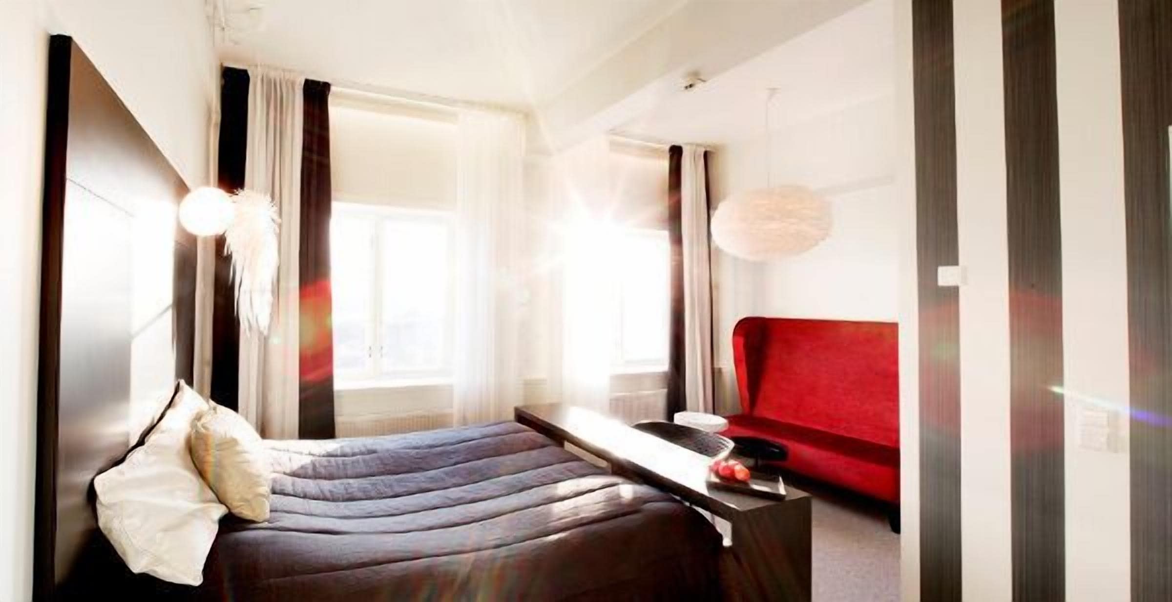 Et moderne soveværelse med seng, skrivebord og en rød sofa.