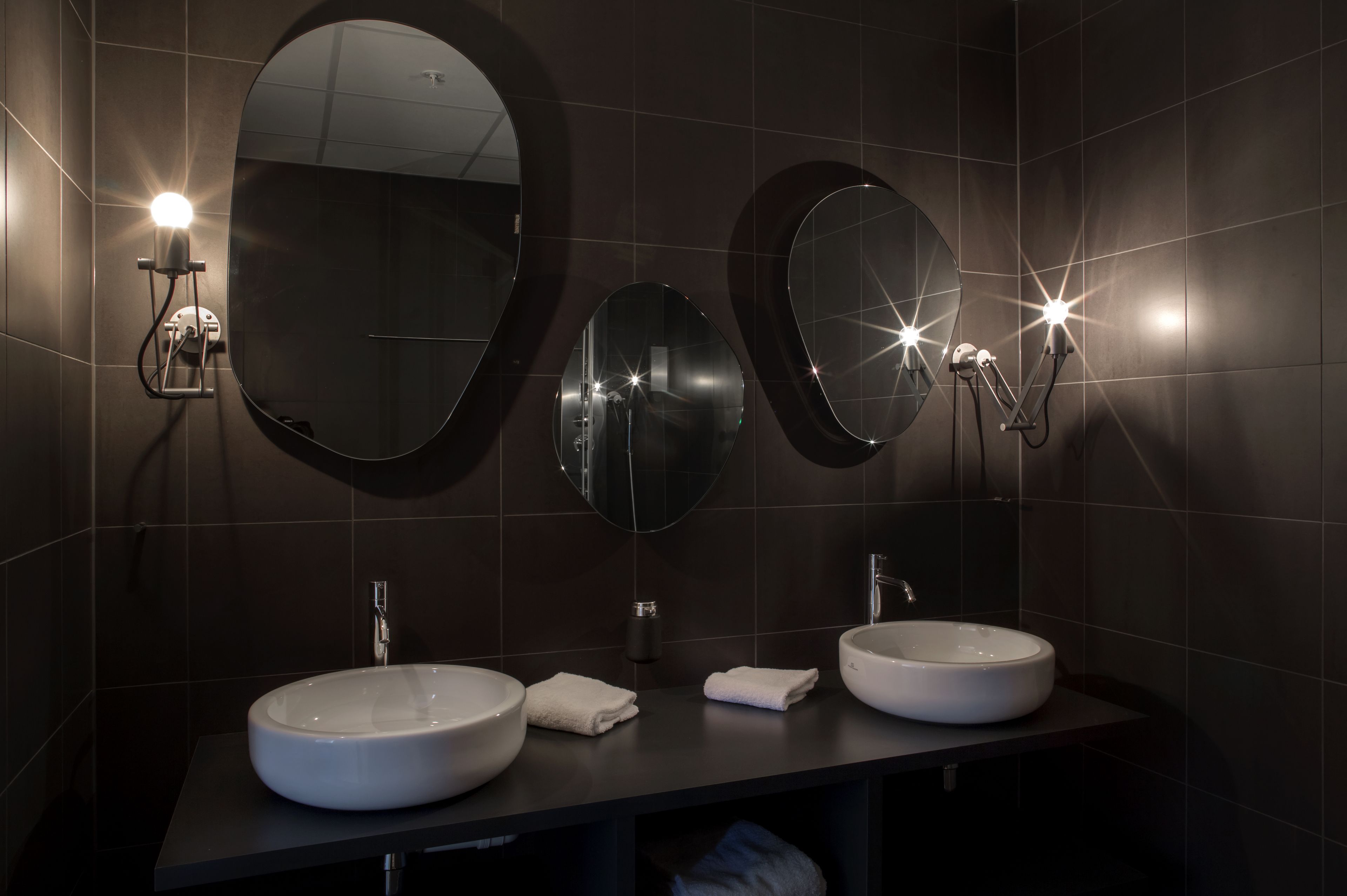 Une salle de bain moderne avec deux miroirs ronds, deux vasques et des luminaires fixés au mur.